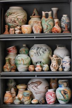 many different vases are on shelves in a room