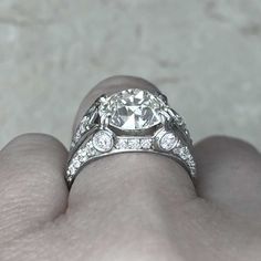 a close up of a person's hand with a diamond ring on their finger