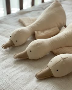 three stuffed animals laying on top of a bed next to each other in the shape of dolphins