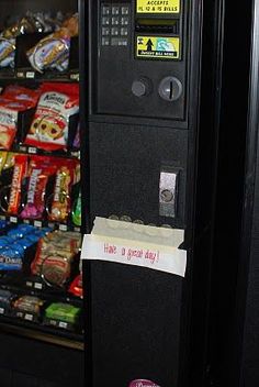 a vending machine that is next to some snacks and candy bar items on the shelf