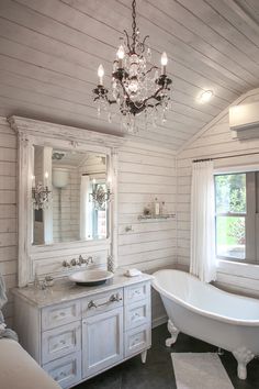 a bathroom with a claw foot tub and chandelier hanging from it's ceiling