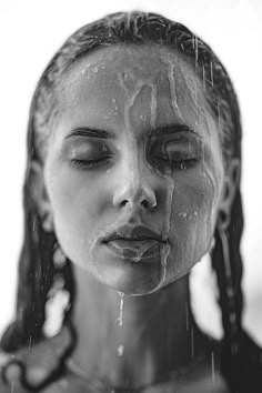 a woman with her eyes closed and water dripping from her face in black and white