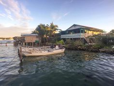 there is a boat in the water next to some houses on stilts and palm trees