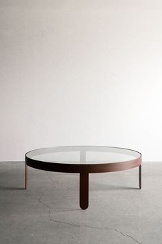 a round glass table sitting on top of a cement floor next to a white wall