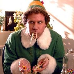 a man wearing a party hat and eating spaghetti with his hands in front of him