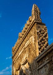 a tall tower with a clock on it's side against a bright blue sky