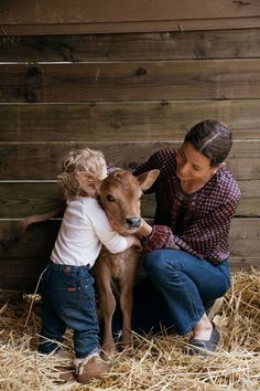 a woman and child petting a baby goat