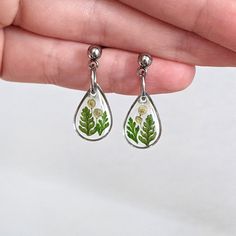 Fern earrings. Pressed flower dangle earrings. Tiny leaf studs. Small fern earrings. Green leaf jewelry. Small nature jewelry. Dainty resin earrings. Real fern leaf plant jewelry. Gift for gardener. Gift for plant lover. Lightweight. These tiny teardrop dangle earrings are handmade and feature real fern leaves and other nature bits encased in resin. Available in gold or silver with black or clear background as well as in tiny or medium size, and featuring a ball stud. Minimalist and earthy, grea Silver Pressed Flowers Drop Earrings, Fern Earrings, Nature Themed Wedding, Gift For Plant Lover, Plant Jewelry, Gift For Gardener, Tiny Pendant, Fern Leaves, Flower Dangle Earrings