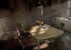 an old table and chairs in a run down room with sunlight streaming through the windows