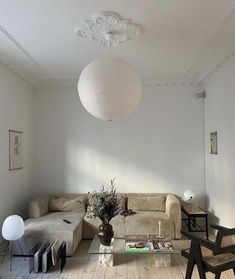 a living room filled with furniture and a lamp hanging over the top of it's head