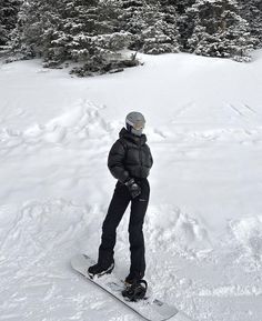 a man riding a snowboard down a snow covered slope