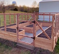 a fenced in area with plants and gravel on the ground next to a barn