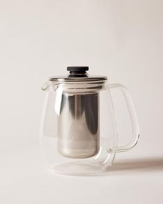 a glass teapot with a black lid and strainer in the shape of a coffee pot