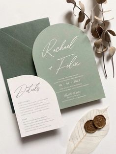 the wedding stationery is laid out on top of an envelope, with two coins