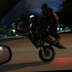 a man riding on the back of a motorcycle at night