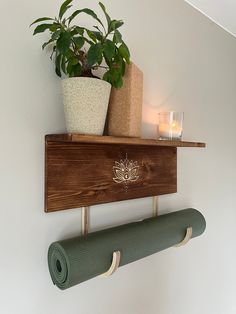 a potted plant on top of a wooden shelf next to a yoga mat and candle