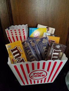 a popcorn bucket filled with lots of different types of snacks and candy bar wrappers