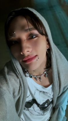 a young woman with piercings on her face and hoodie over her head is looking at the camera