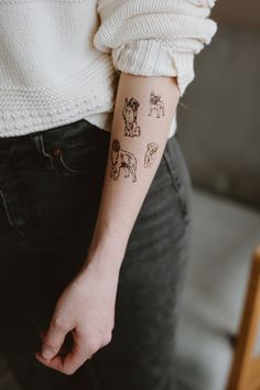 a woman's arm with tattoos on it, showing the dog and cat symbols