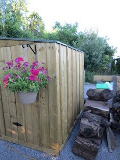 a potted plant sitting on top of a wooden fence next to logs and flowers