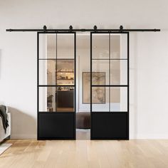 a living room with white walls and wooden flooring next to a sliding glass door