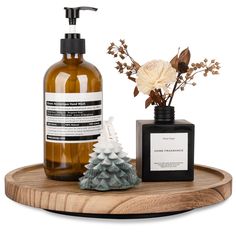 a soap dispenser, bottle and vase on a wooden tray