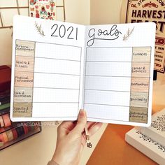 a person holding up a planner with the words 2021 goals written on it in front of them