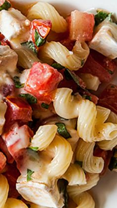 pasta salad with bacon, tomatoes and spinach in a white bowl