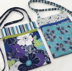 two purses are sitting next to each other on a white surface with blue, green and purple flowers