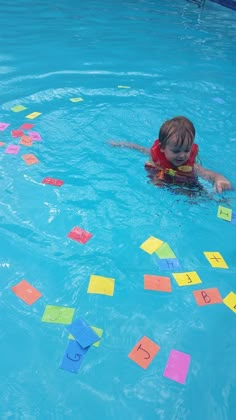 a child in a swimming pool surrounded by post - it notes and water toy blocks