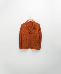 an orange sweater hanging on a white wall