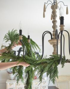 a chandelier is decorated with greenery and candles