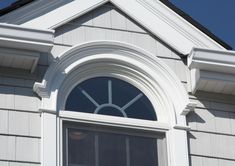 an arched window on the side of a house with blue sky in the back ground