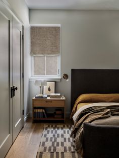 a bed sitting next to a window in a bedroom on top of a hard wood floor