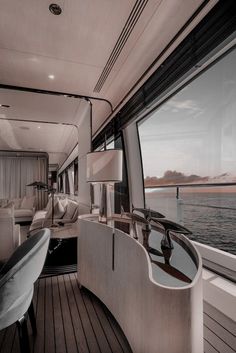 the interior of a luxury yacht looking out over the water at sunset, with couches and lamps