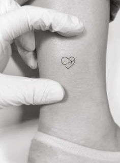 a person wearing gloves holding up a small heart tattoo on their right side ribcage