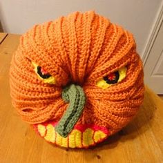 an orange knitted pumpkin sitting on top of a wooden table