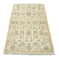 an antique persian rug with blue and beige flowers on the bottom, fringes around the edges