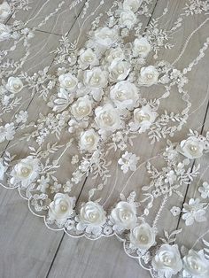 a white lace with flowers and pearls on the bottom is laying on a wooden floor