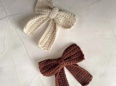 two crocheted bows are laying next to each other on a white table top