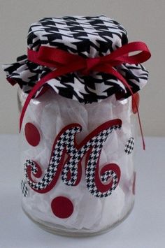 a glass jar with red and black polka dots on the lid is decorated with a monogrammed ribbon