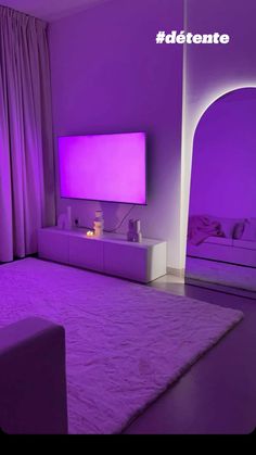 a bedroom with purple lighting and a large screen tv on the wall in front of it