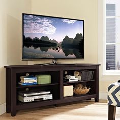 a flat screen tv sitting on top of a wooden entertainment center next to a window