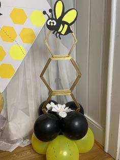 some balloons are sitting on the floor next to a honeycomb with a bee decoration