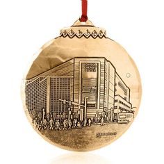 a silver ornament with a drawing of people walking in front of a building