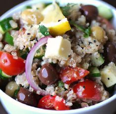 a white bowl filled with rice, olives, tomatoes and other veggies