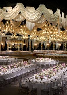 a banquet hall with tables and chairs covered in white draping, chandeliers and floral centerpieces