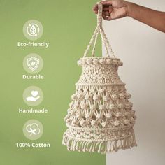 a hand holding a white hanging basket with tassels on it and the words eco - friendly, durable, handmade, 100 % cotton