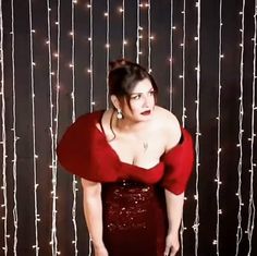 a woman in a red dress posing for the camera with her hands on her hips