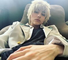 a man with blonde hair sitting on top of a couch next to a person's hand